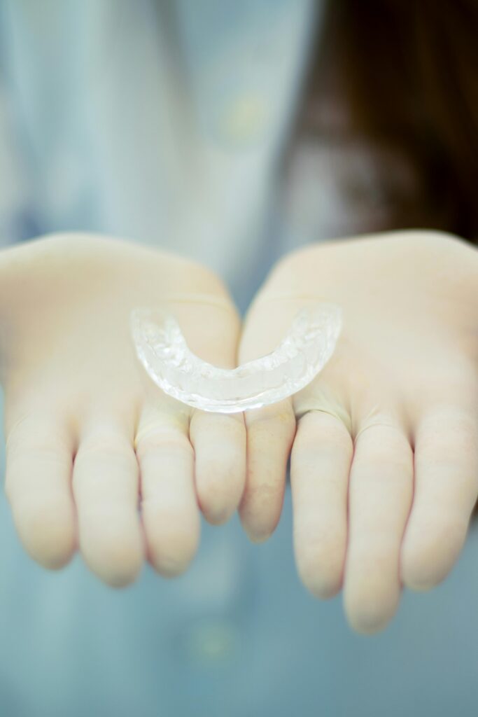 Focused image of gloved hands presenting a transparent dental retainer
