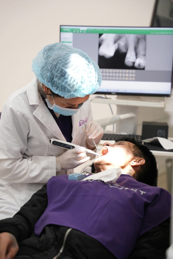 pexels-photo-19764018-19764018 Dentist examines patient in clinic with medical equipment and X-ray display.