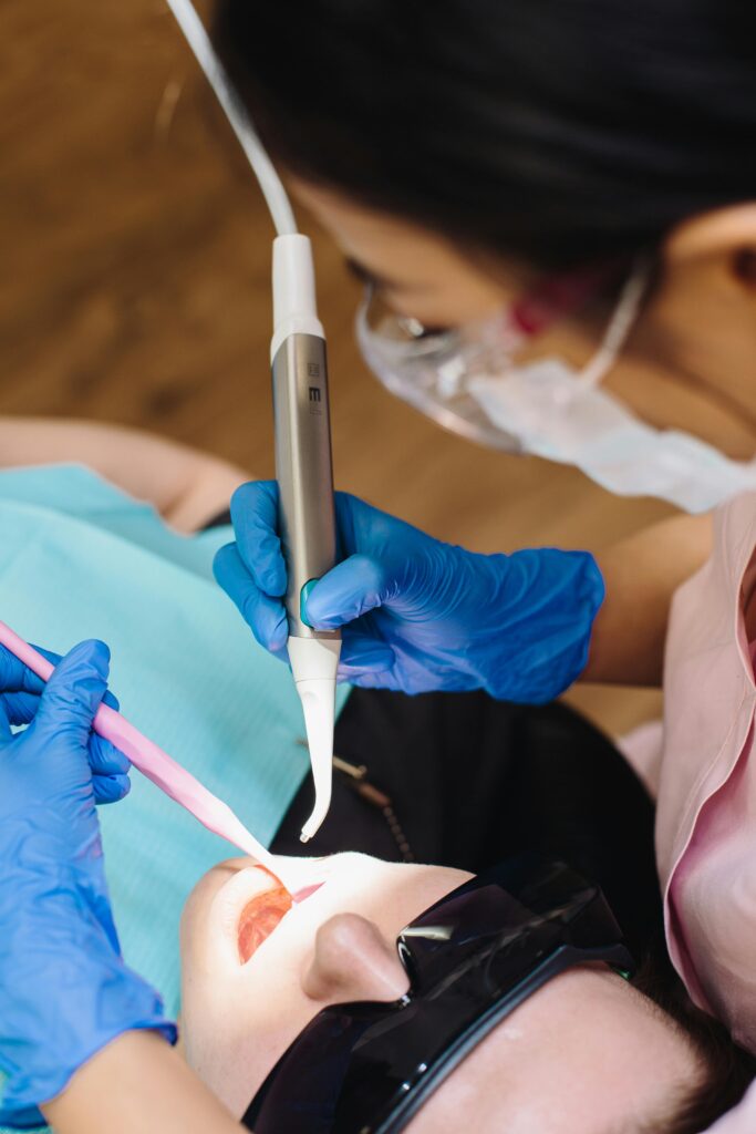 pexels-photo-4687254-4687254 A dentist performs a procedure using modern dental equipment on a patient wearing protective glasses.