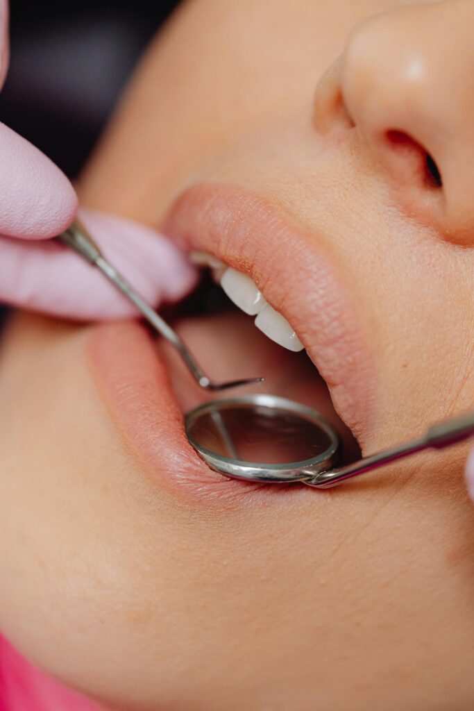 pexels-photo-6627531-6627531 Close-up view of a patient's dental check-up using dental mirror and tools.